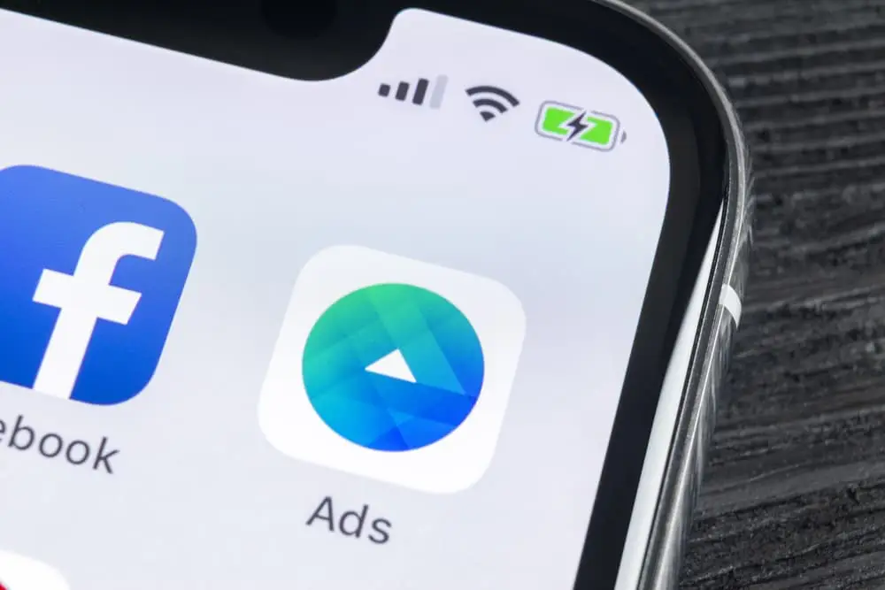 A close-up view of a smartphone screen displaying the Facebook Ads app icon, with the Facebook logo